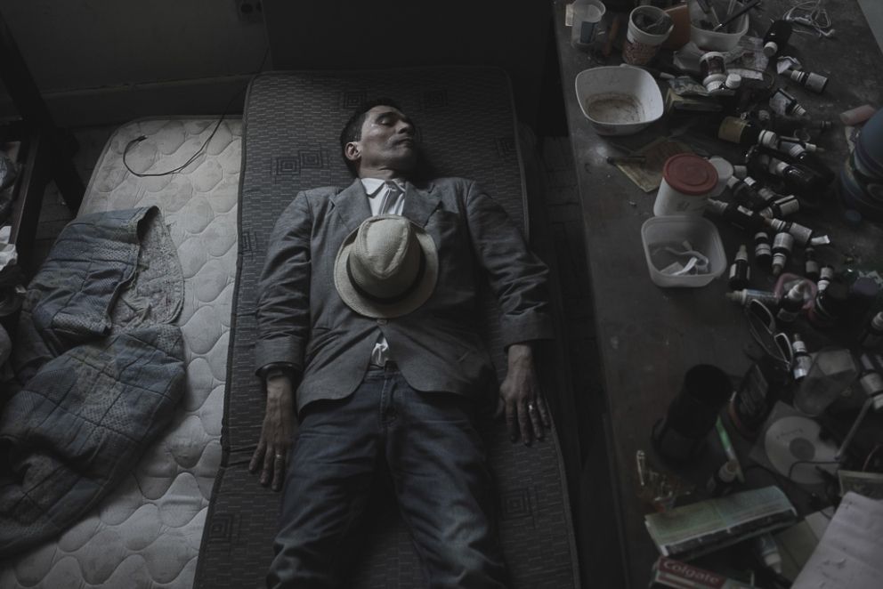 A photograph of a man who falls asleep on his bedroom full of empty drug bottles and pills, used to treat mental disorders. Some people within the 'Marconi' building, are living in this major city without any contact with family ir relatives since they decided to leave their hometowns in search of better opportunities.